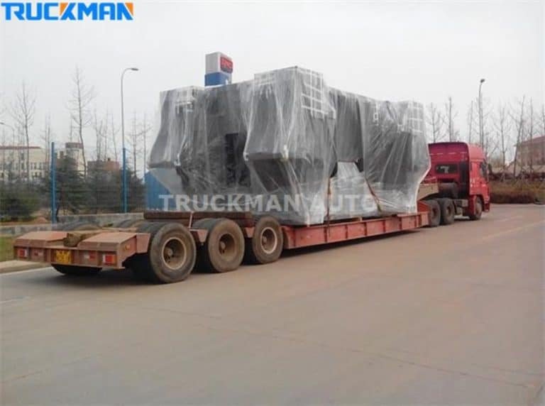 Semirremolque de plataforma baja que transporta grandes equipos industriales cubiertos.