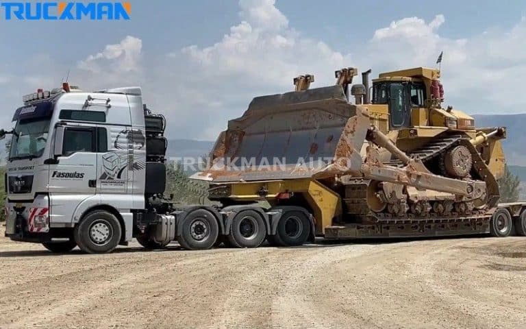 Camión semirremolque de chasis bajo para cargas pesadas que transporta un gran bulldozer amarillo, demostrando la gran capacidad de carga y el diseño robusto del remolque.
