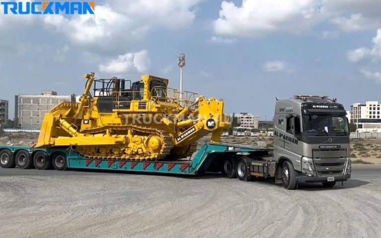 Camión semirremolque de plataforma baja cargando una gran excavadora amarilla: construcción robusta y eficacia en el transporte