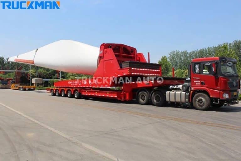 Semirremolque de plataforma baja cargado con largas palas blancas de aerogenerador, potente capacidad de carga pesada