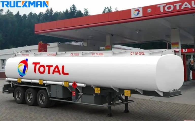Un remolque cisterna de combustible blanco de la marca TOTAL en una estación de servicio, destacando su gran capacidad de volumen para el transporte de productos petrolíferos.